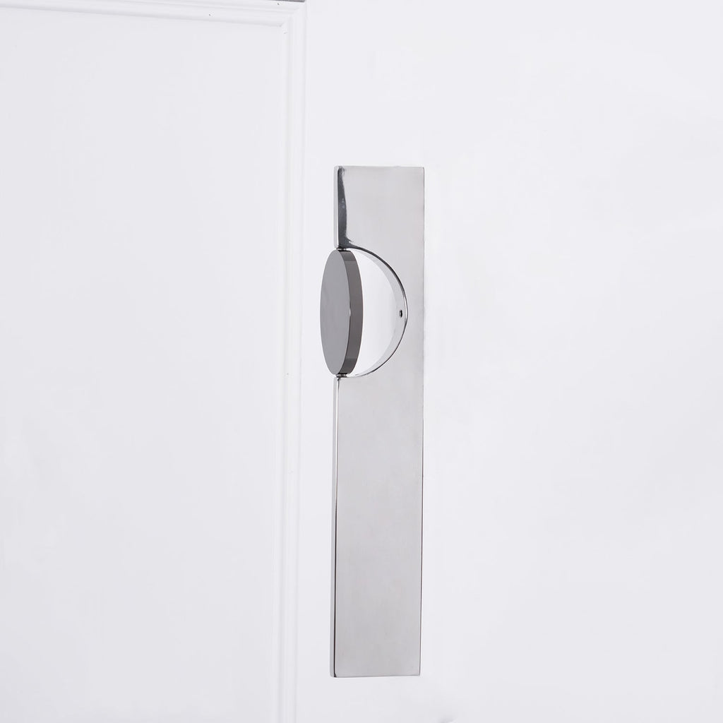 Sculptural chrome wall lamp casting a soft shadow pattern