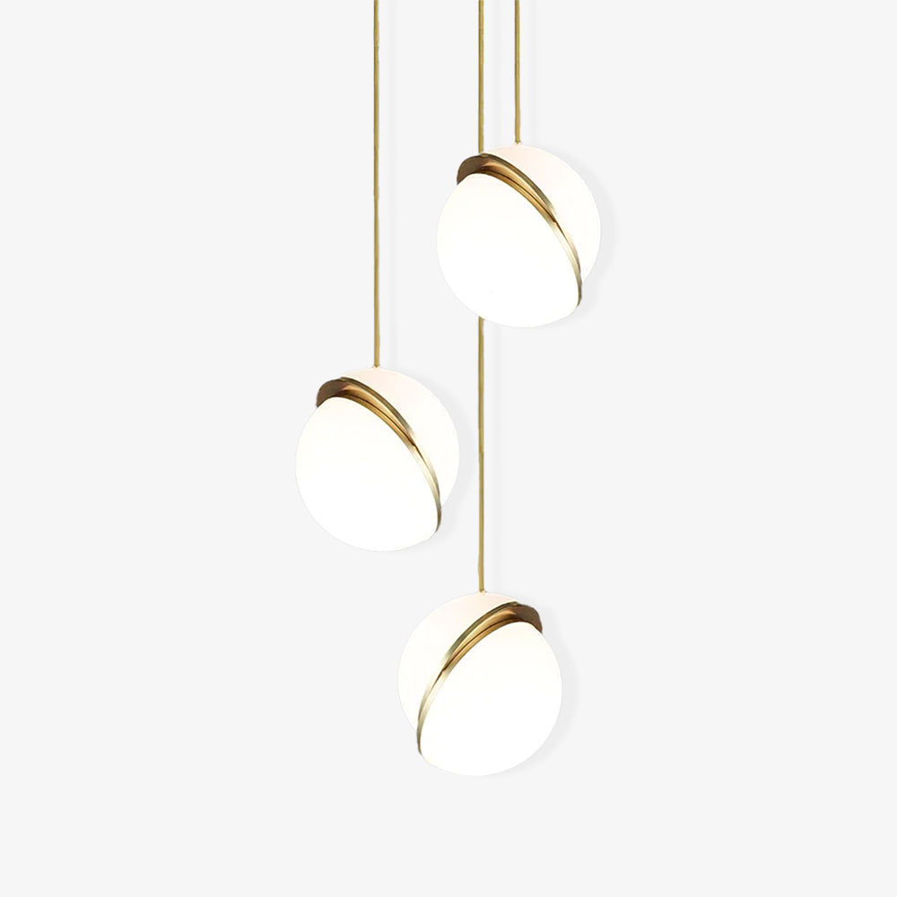 On a plain light-grey backdrop, three brass-crescent pendants trail at different lengths, from Clérachic.