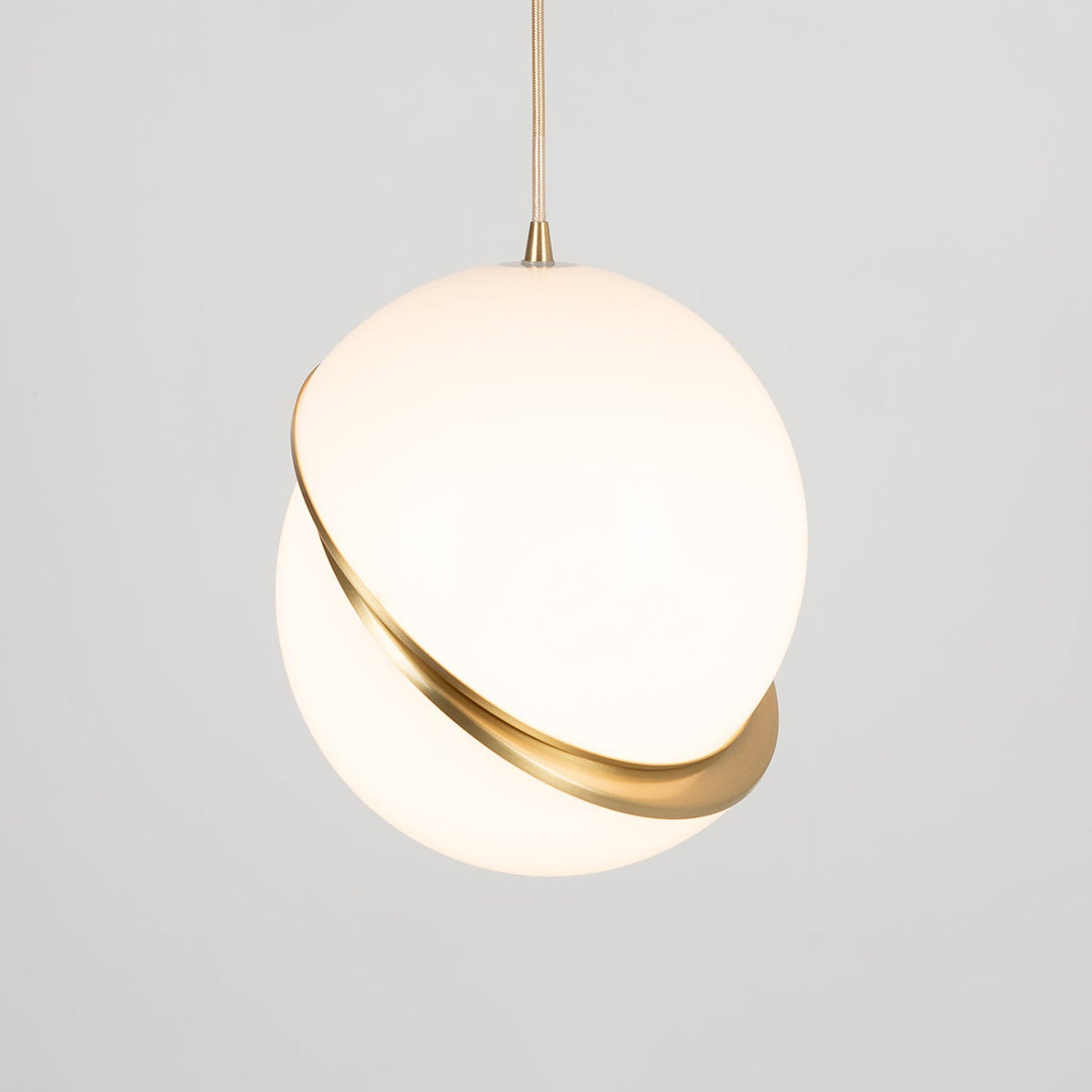 Hanging low with extra cord showing above, this Clérachic pendant glows softly against a plain grey backdrop.