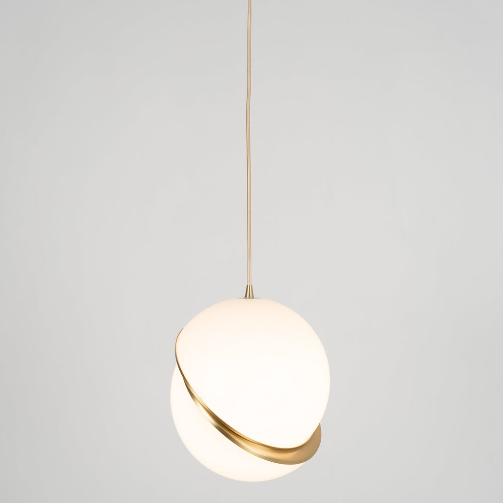 This Clérachic pendant hangs centred on a long brass cord, mid-size against a plain grey backdrop.