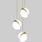 In a column against a grey backdrop, three brass-crescent pendants descend, from this Clérachic fixture.