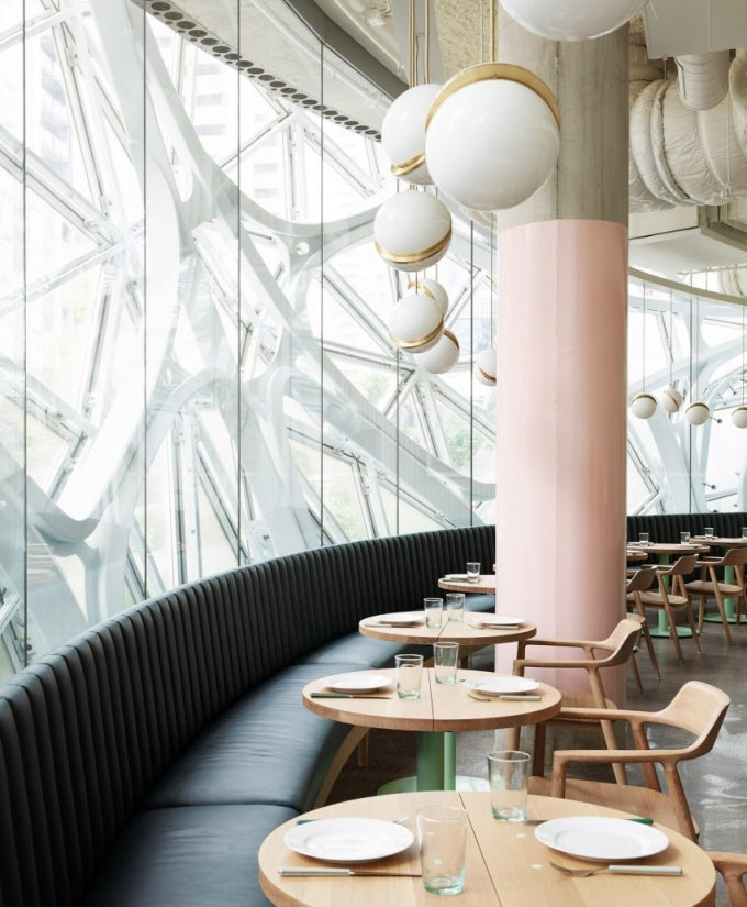 Beneath a glass and steel atrium roof, clusters of opal pendants with brass crescents hang, from Clérachic.