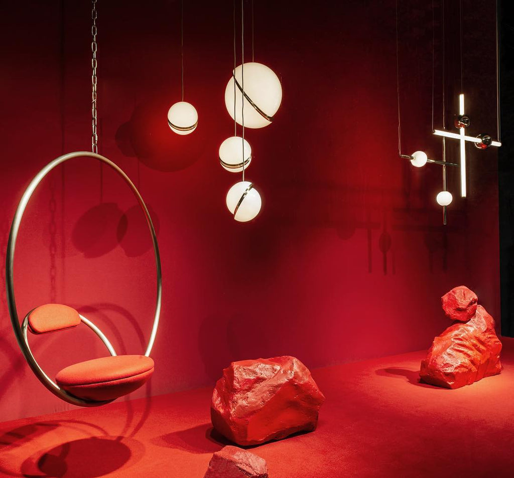In a styled red room beside a brass hoop chair and rock props, clusters of this Clérachic pendant hang.