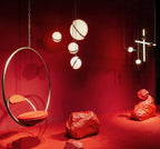 In a styled red room beside a brass hoop chair and rock props, clusters of this Clérachic pendant hang.