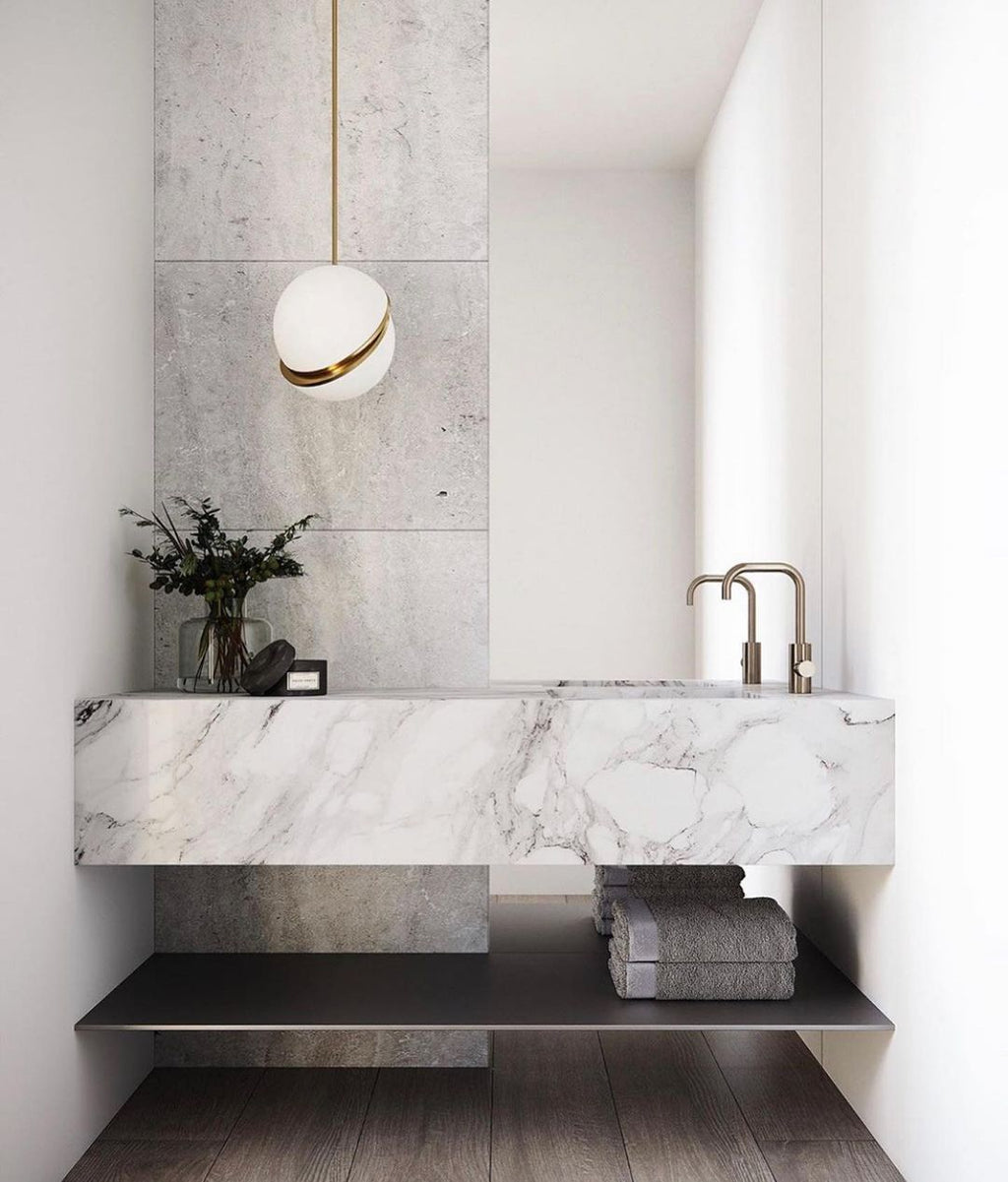 Above a floating marble vanity with black tapware, a single Clérachic pendant hangs.