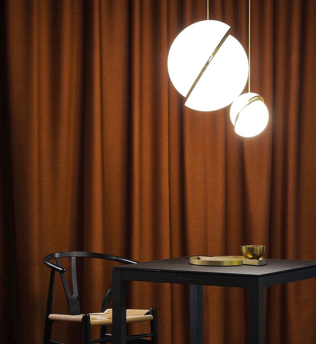 Against rust-coloured curtains above a black dining table, two of this Clérachic pendant hang.