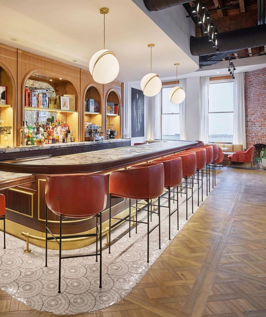 Above a bar with red stools and a herringbone floor, pendants of this Clérachic fixture hang.