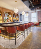 Above a bar with red stools and a herringbone floor, pendants of this Clérachic fixture hang.
