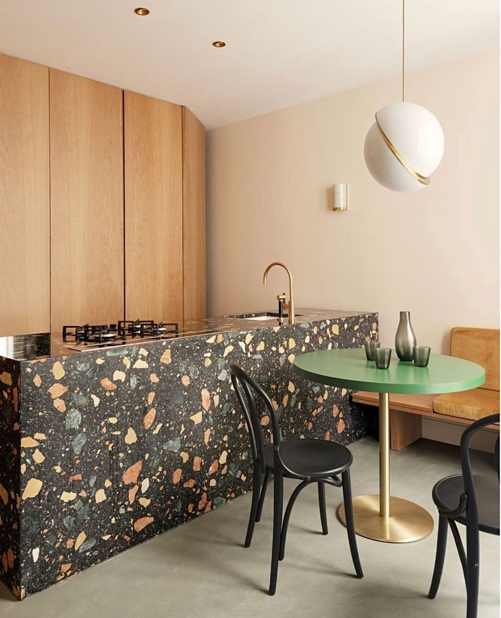 Above a terrazzo kitchen island with a green side table, a single Clérachic pendant hangs.