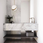 Above a marble vanity with brass tapware and folded grey towels, a single Clérachic pendant hangs.