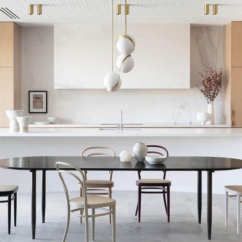 Above a marble kitchen island set for dining, clustered Clérachic pendants hang.