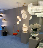 In a showroom beside a hanging chair and a fluted chandelier, clusters of this Clérachic pendant hang.