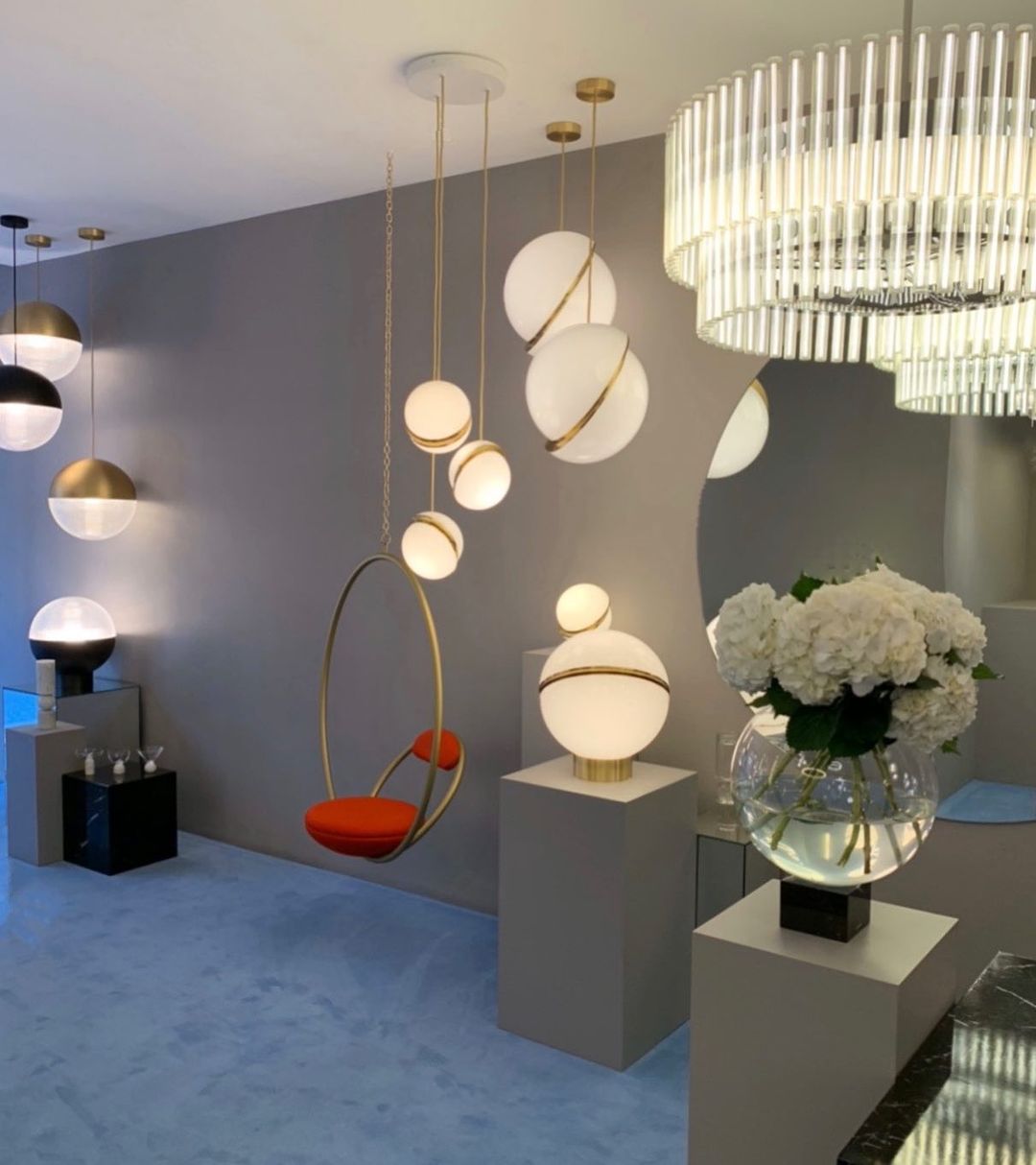 In a showroom beside a hanging chair and a fluted chandelier, clusters of this Clérachic pendant hang.