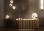 Above a ribbed brass kitchen island, clustered opal pendants with brass crescents hang, from Clérachic.