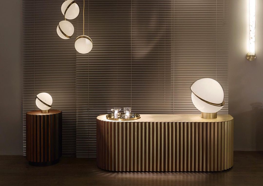 Above a ribbed brass kitchen island, clustered opal pendants with brass crescents hang, from Clérachic.