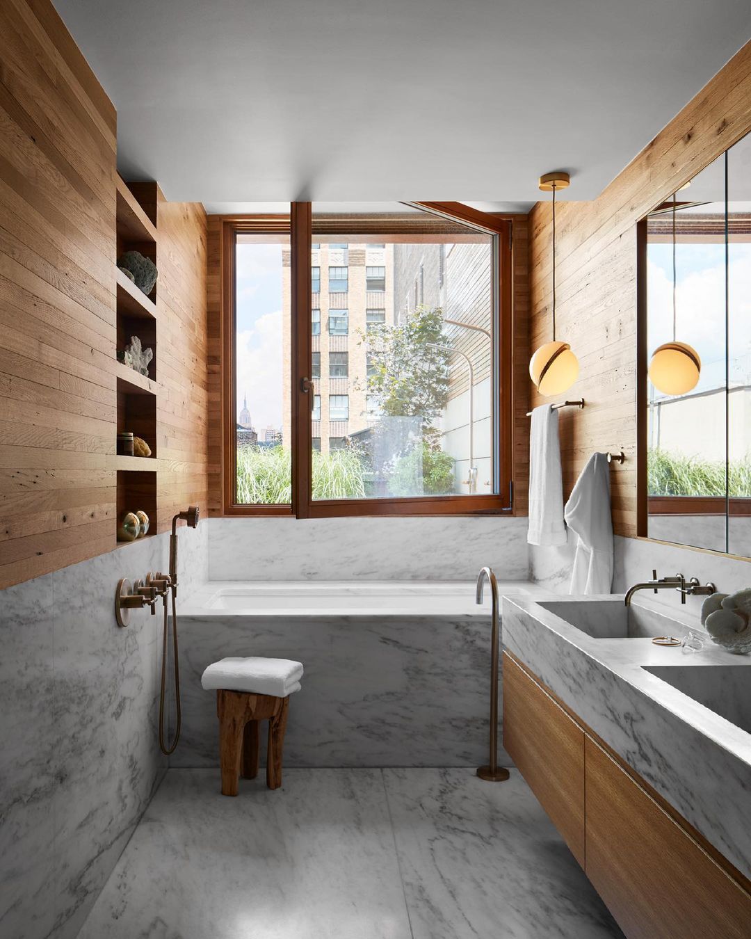 Beside a timber-lined bathroom with a marble tub and window, a single Clérachic pendant hangs.