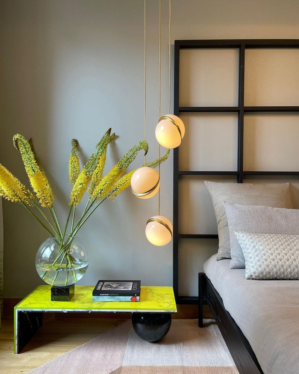 Beside a vase of yellow flowers on a chartreuse table, a pair of these Clérachic pendants glows softly.