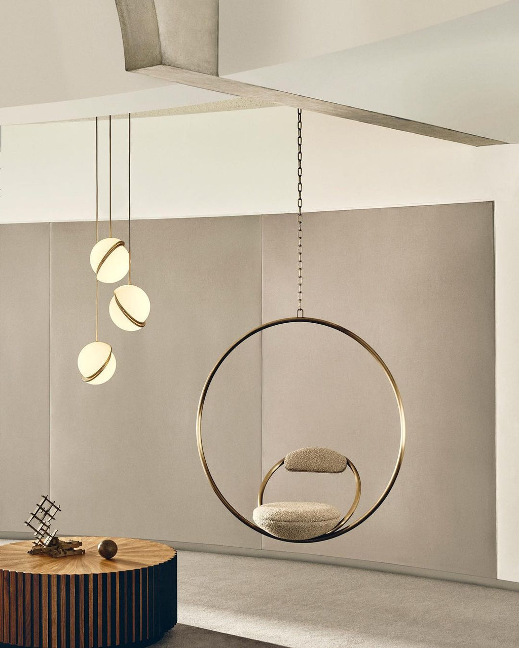 Beside a brass hoop chair on a soft pink backdrop, clustered pendants hang from this Clérachic fixture.
