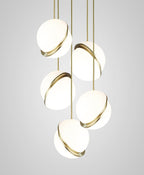 At staggered heights against a plain backdrop, five brass-crescent pendants cluster, from this Clérachic fixture.