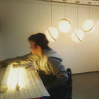 Low over a lit work table, four brass-crescent pendants of this Clérachic fixture catch the glow.
