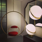 Beside a brass hoop chair with a red seat cushion, clusters of this Clérachic pendant hang close together.