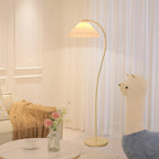 Pleated floor lamp adding soft ambience next to a reading chair