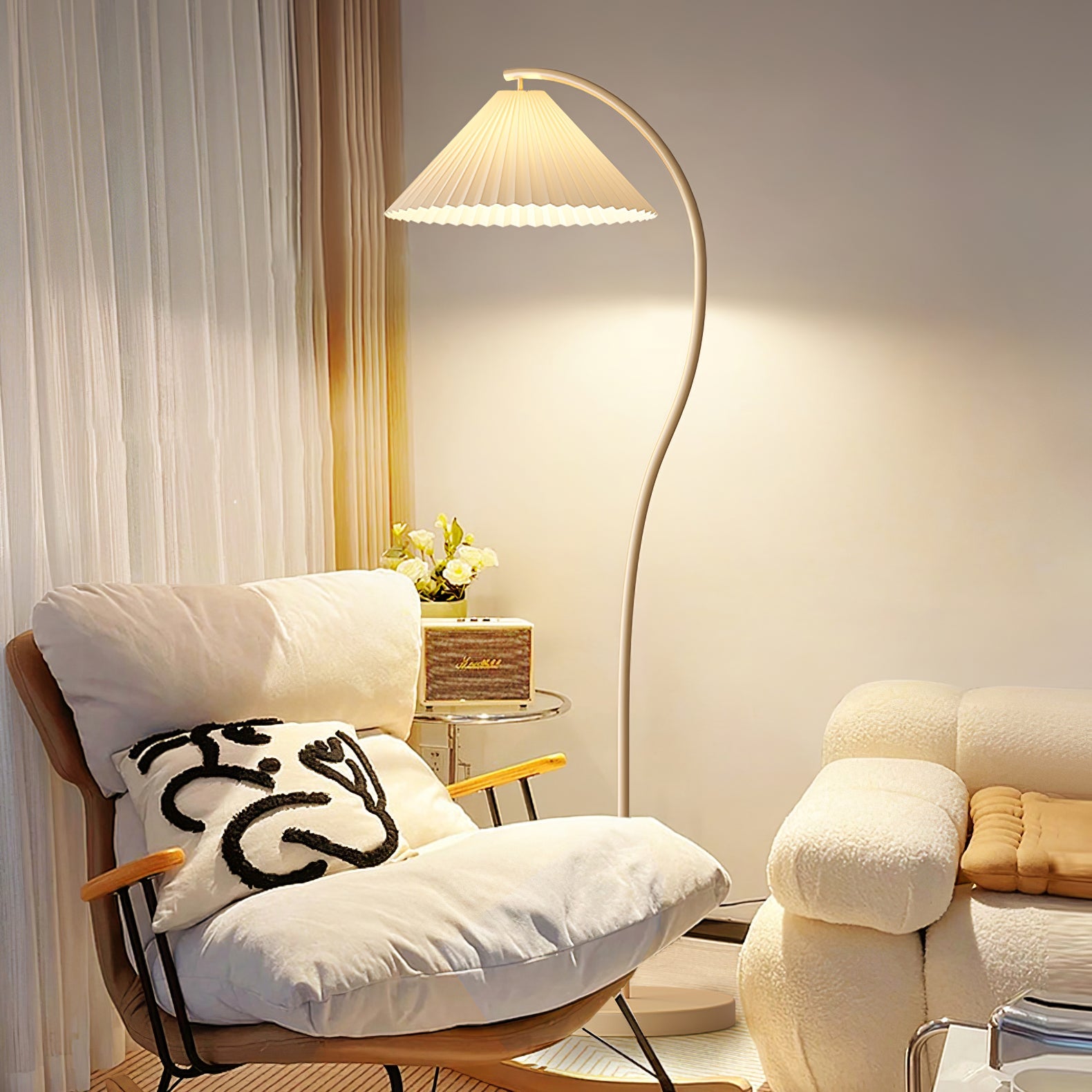Floor lamp with pleated linen shade lit in a softly furnished room
