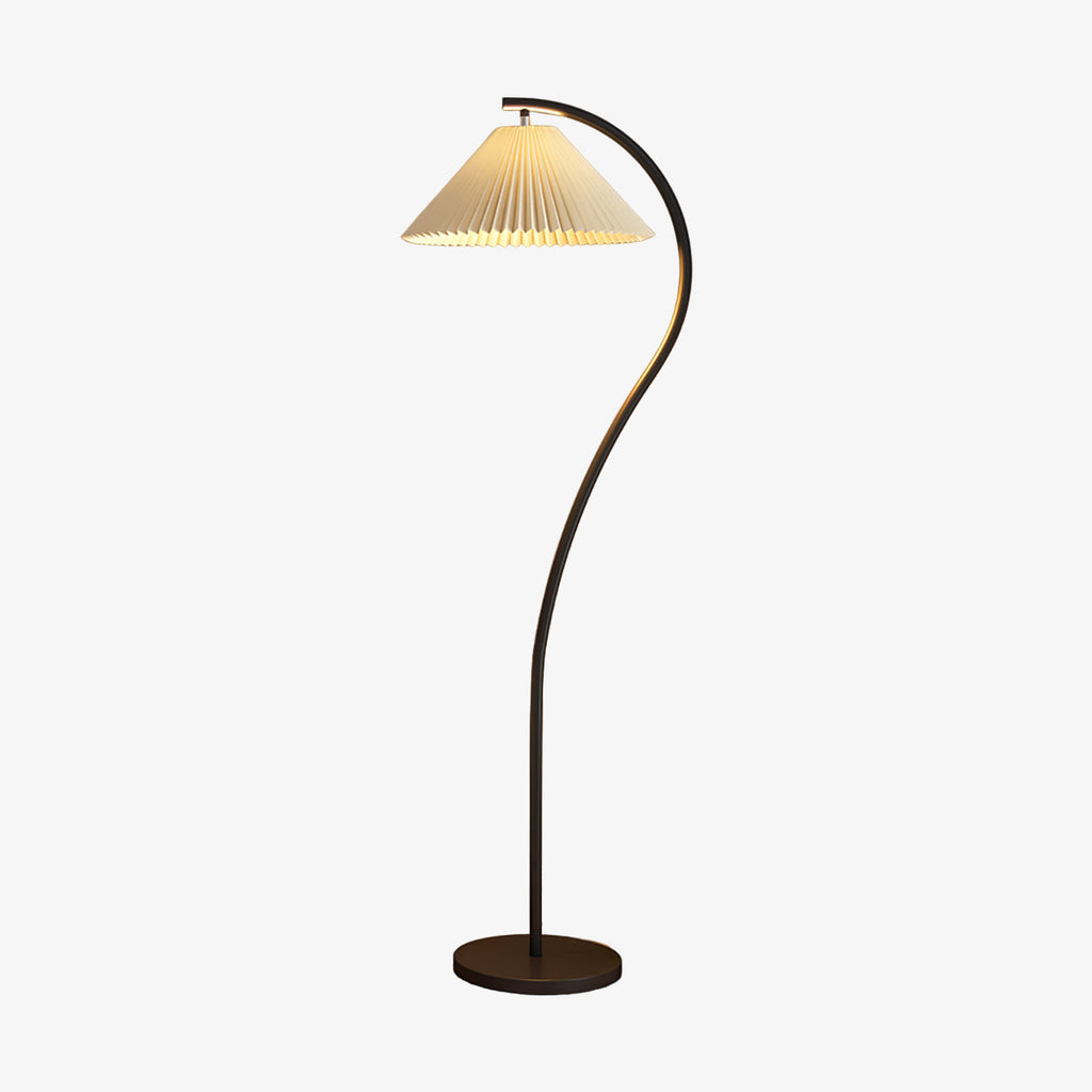 Pleated linen shade glowing warmly on the floor lamp beside a sofa