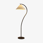Pleated linen shade glowing warmly on the floor lamp beside a sofa