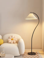 Pleated linen floor lamp lit in a calm neutral room