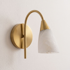 Mounted on a plain wall, this Clérachic sconce shows its brass arm curving up to an angled alabaster cone shade.