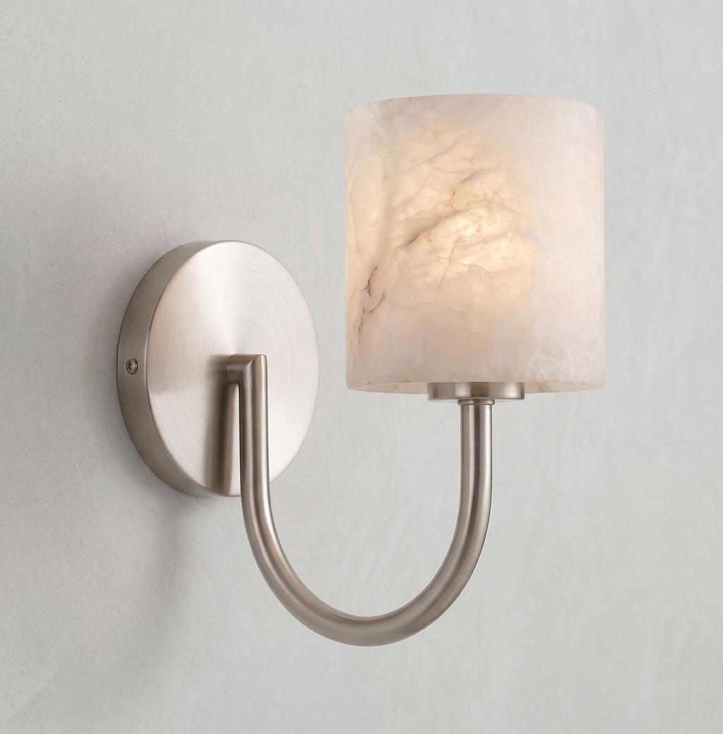 Close view of the curved arm and glowing alabaster drum shade on this brushed nickel Clérachic sconce.