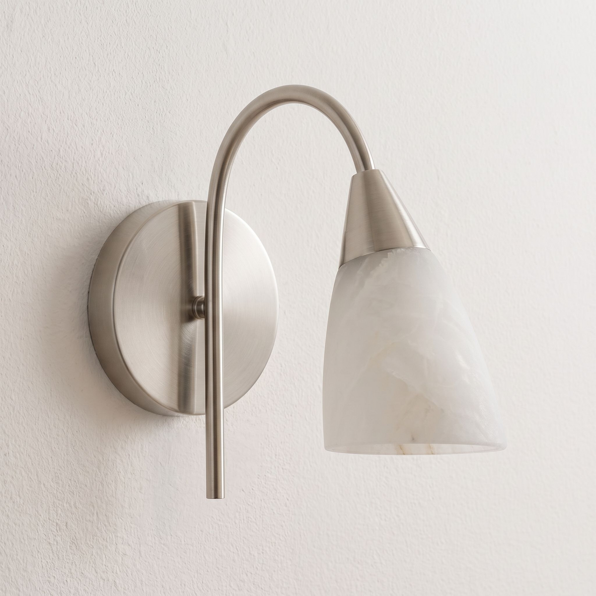 Shown close on a plain wall, this Clérachic sconce's nickel finish supports a forward-tilted alabaster cone.
