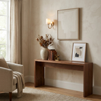 Above a walnut console styled with a vase and framed art, this brass Clérachic wall sconce glows warmly.