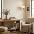 In a reading corner with an upholstered armchair, a brass Clérachic wall sconce lights a low storage bench below.