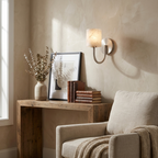 This Clérachic wall sconce in brushed nickel glows above a reclaimed-wood console styled with books.