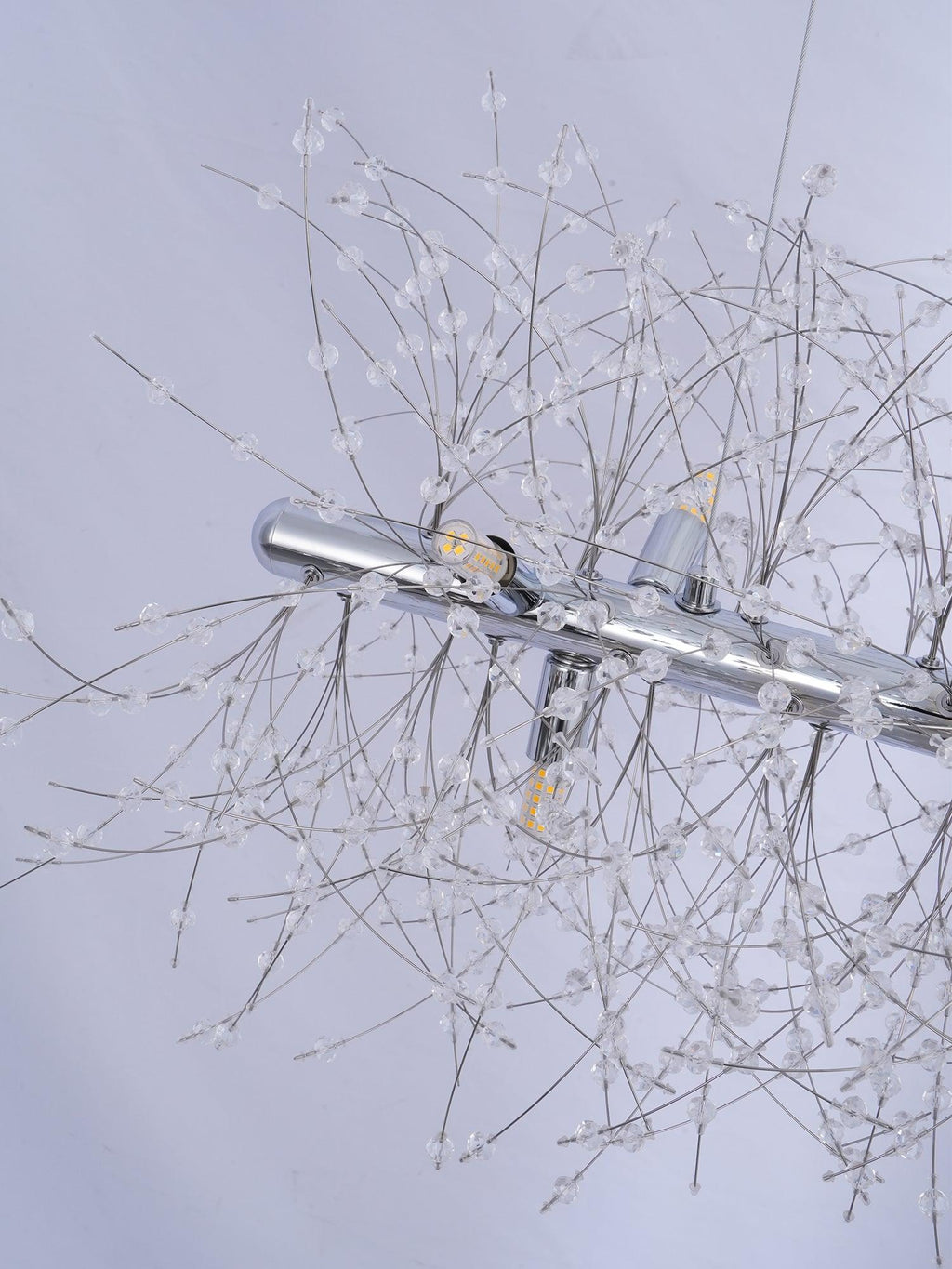 Close-up of a chrome mounting bar and fine crystal-tipped branches, a different Clérachic fixture from this round chandelier.
