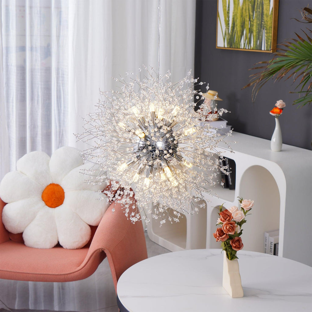 A pink accent chair with a white daisy pillow sits beneath this Clérachic chandelier near a marble-topped table.
