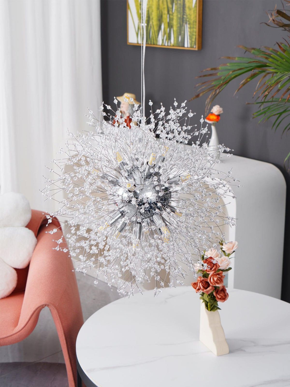 This Clérachic chandelier hangs above a small round table styled with dried flower stems and tiny bird figurines.