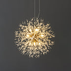 This Clérachic chandelier hangs lit against a dark charcoal wall, its crystal-tipped branches glowing warmly.