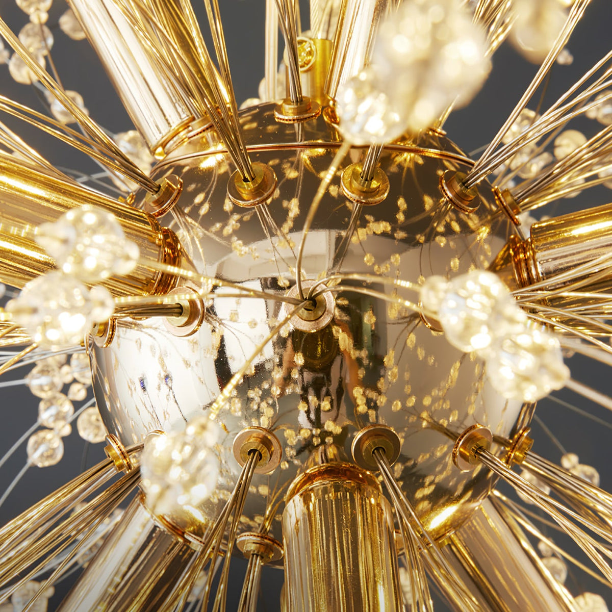 Extreme close-up of the gold centre hub on this Clérachic chandelier, showing several lit bulbs and converging branches.