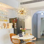 This Clérachic chandelier hangs above a round dining nook with open shelving, a stainless fridge and pastel-coloured mugs.