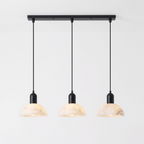 In matte black, this Clérachic pendant shows its three domed alabaster shades strung from a straight bar.
