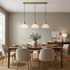 Three brass-mounted alabaster domes on this Clérachic pendant hang above a walnut table with beige upholstered chairs.