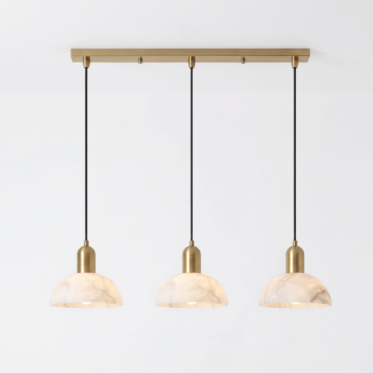 Seen in full against white, this brass Clérachic pendant fans three alabaster domes from a linear bar.