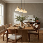 Over a rustic wood table with wishbone chairs, this brass Clérachic pendant lights a dining room.