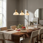 Above a walnut table near a round mirror, this brass Clérachic pendant lights a dining corner.