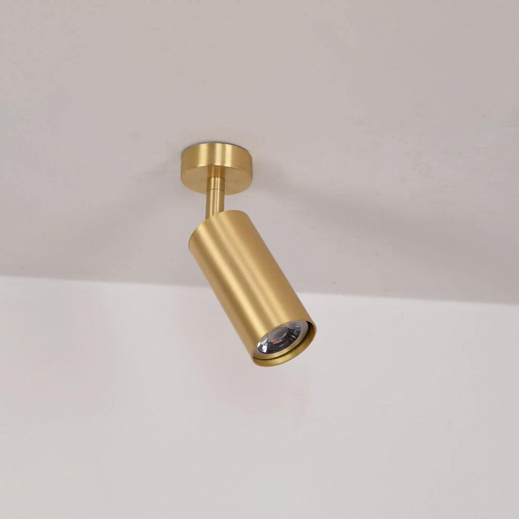 Brass cylinder spotlight wall light mounted on a pale wall