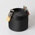 Close view of this Clérachic downlight in black from above, its spring-clip mounts open and unlit, on a plain backdrop.