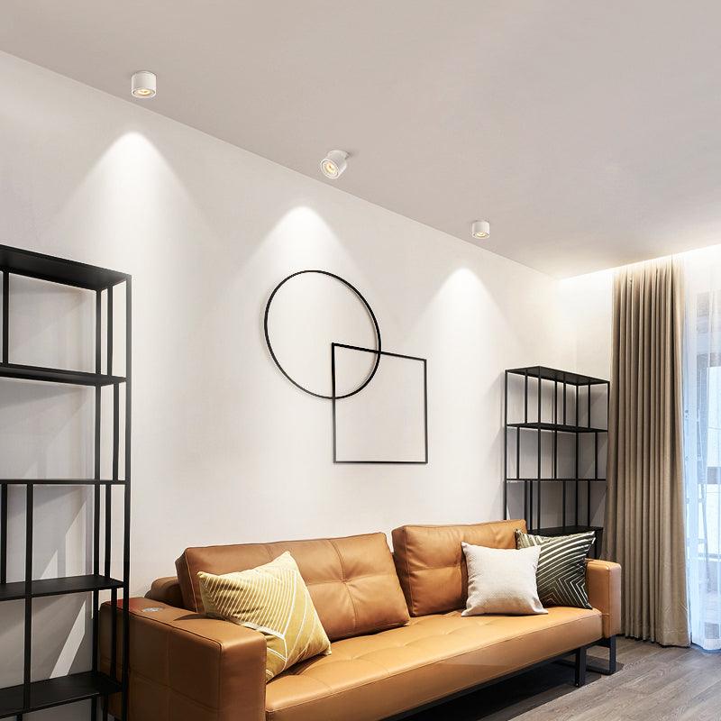 White units of this Clérachic downlight light the same living room, tan leather sofa and circular wall art visible.